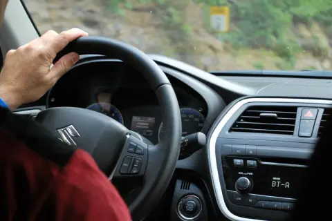 Ręka na kierownicy Suzuki. Rozpoczynają się formalności związane z kupnem używanego samochodu, czas na jazdę próbną.