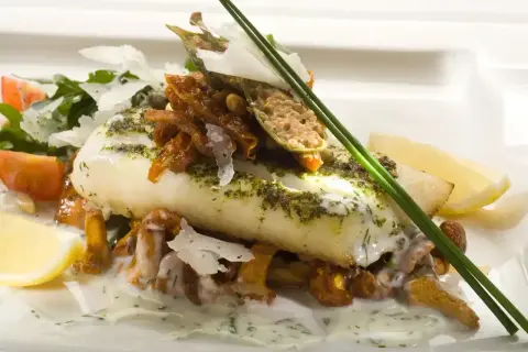 Wykwintne danie z rybą halibut, podane z kurkami, pomidorkami i cytryną.