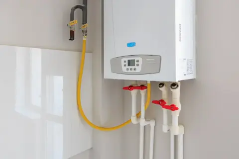 Installation d'un nouveau ballon d'eau chaude Baxi. Tuyaux de gaz et d'eau avec robinets rouges.