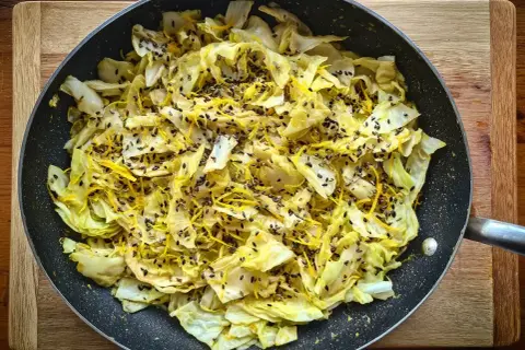 Stekt spetskål med citronskal och svarta sesamfrön i en stekpanna. Enkel och god rätt att grilla spetskål.