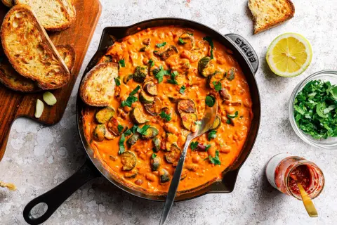 Herzhafte zucchini pfanne in cremiger Sauce, garniert mit frischer Petersilie und serviert mit geröstetem Brot.