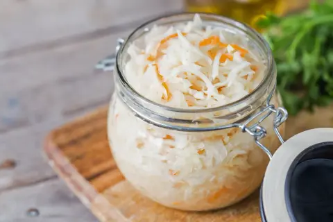 Glas mit Sauerkraut, bereit zum Kohl fermentieren. Frische Kräuter im Hintergrund.