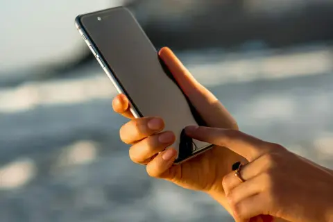 Dłoń z pierścionkiem pokazuje, jak włączyć iPhone'a, dotykając ekranu.