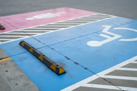 Niebieski pas z symbolem wózka inwalidzkiego i różowy z postacią ludzką. Czy parking dla niepełnosprawnych jest płatny?