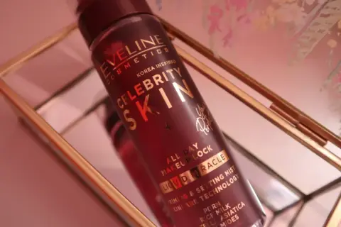 Butelka mgiełki Eveline Celebrity Skin w złotym stojaku.