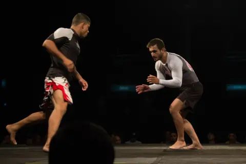 Two fighters face off, their stances showing the endurance and stamina required for this intense grappling match.