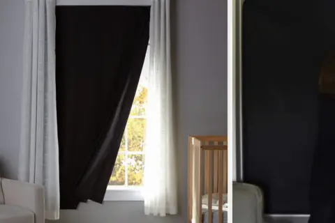 Habitación infantil con cuna y una ventana sin persiana, cubierta por cortinas blancas y un panel negro para oscurecer.