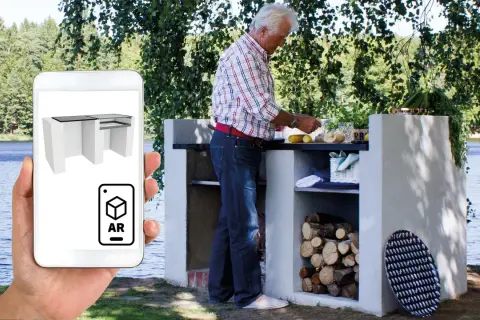 En man förbereder mat vid en murad grill vid en sjö. En telefon visar en 3D-modell av en Murad grill i AR.