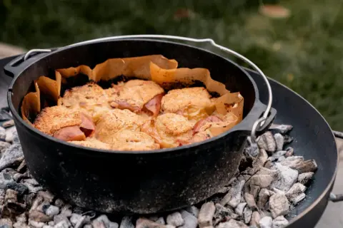 Ein Gusseisentopf mit einem leckeren Crumble, der über glühender Kohle für das **Winter grillen** zubereitet wird.