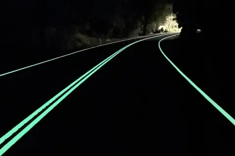 Route de nuit avec marquage lumineux vert, un logo marquage ce discret sur le côté.