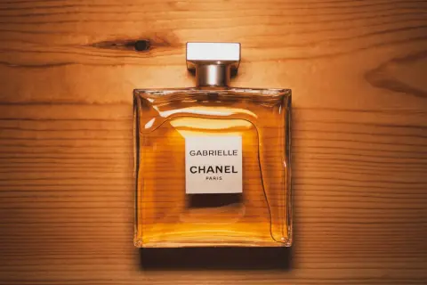 Elegancka butelka perfum Chanel Gabrielle na drewnianym tle. Czy to właśnie takich perfum używają gwiazdy?