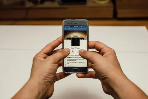 Ręce trzymają telefon z profilem FB. Chcesz wiedzieć, jak zmienić zdjęcie profilowe na FB, żeby nikt nie lajkował?
