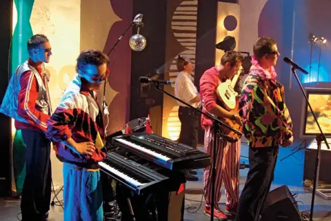 Zespół grający disco polo lata 80 90. Kolorowe stroje, syntezatory i gitara tworzą klimat tamtych lat.