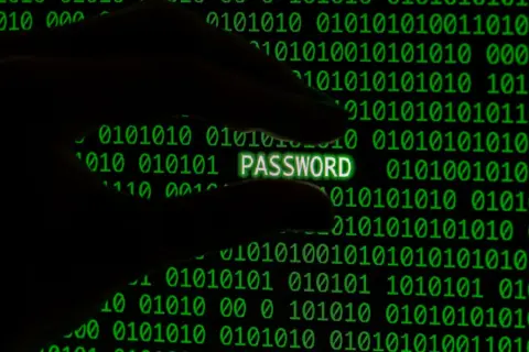 Dłoń trzyma świecący napis PASSWORD na tle zielonego kodu binarnego. To hasło 8-znakowe.