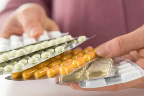 Hände halten mehrere Blisterpackungen mit Tabletten und Kapseln. Die Frage, darf man Tabletten mit ins Flugzeug nehmen, wird hier visuell thematisiert.