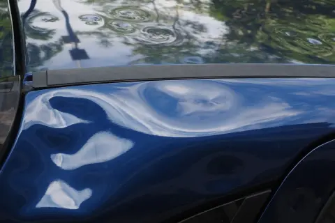 Blauer Lack mit deutlichem Hagelschaden, typisch für ein Leasingfahrzeug nach einem Unwetter.
