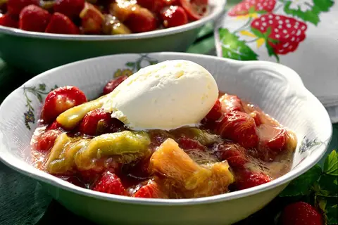 En skål med rabarberkompott och kardemumma, toppad med en kula vaniljglass. En härlig sommardessert.