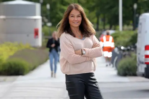 Lena Bivner, med armarna i kors, ler mot kameran utomhus.