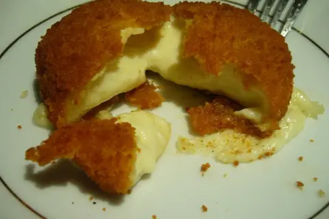 Pyszny camembert w panierce, z którego wypływa gorący, ciągnący się ser. Idealna przekąska na ciepło.
