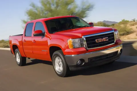 Czerwony pickup GMC Sierra z napędem 4x4 jedzie po pustynnej drodze.