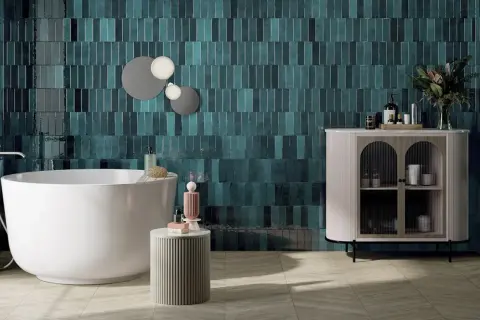 Une salle de bain moderne avec des carreaux muraux bleu sarcelle profonds, une baignoire îlot blanche et un meuble de rangement élégant. Une belle idée couleur salle de bain pour une ambiance chic.
