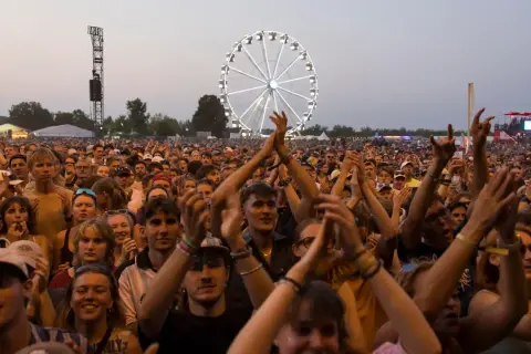 Menschen jubeln beim Highfield Festival Leipzig. Ein Riesenrad leuchtet im Hintergrund.