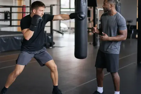 A boxer practices jabs with a trainer watching, counting the punches. The gym has boxing numbers on the wall.