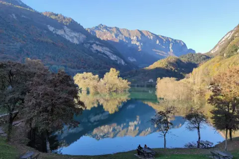 Splendido lago di Tenno in giornata, con montagne maestose e riflessi sull'acqua cristallina. Un angolo di pace autunnale.