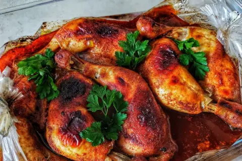 Chrupiące udka pieczone w rękawie, skąpane w aromatycznym sosie, ozdobione świeżą natką pietruszki.