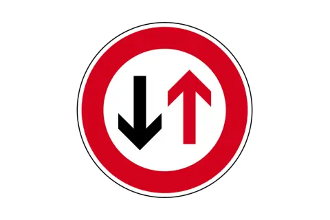 Verkehrsschild: Vorfahrt für den Gegenverkehr. Ein roter Kreis mit weißem Grund zeigt einen schwarzen Pfeil nach unten und einen roten Pfeil nach oben.