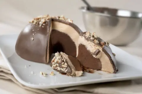 Un delizioso tartufo alla nocciola, con strati di gelato al cioccolato e crema, ricoperto di cioccolato e granella di nocciole.
