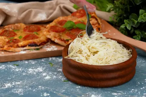 En skål med krispig pizzasallad bredvid en pizza med tomater. Perfekt tillbehör för ditt pizzasallad recept.