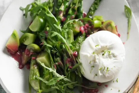 Spargel mit Burrata, grünen Tomaten und Rucola auf einem Teller. Ein köstlicher Frühlingssalat.
