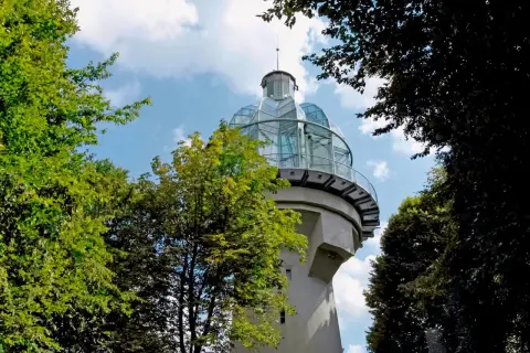 Ein Aussichtsturm mit Glaskuppel, ideal für bergische schweiz wandern. Umgeben von grünen Bäumen und blauem Himmel.