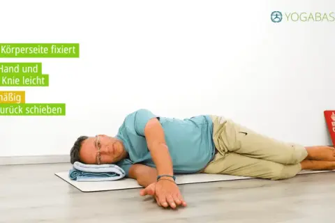 Mann liegt auf der Seite, fixiert untere Körperseite. Oberes Knie und Hand werden sanft vor & zurück geschoben. Was hilft bei Ischiasschmerzen? Yogaübungen!