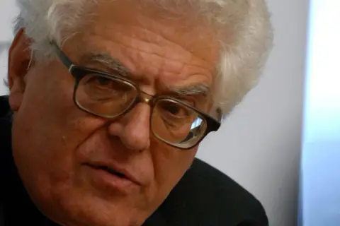 Nahaufnahme eines älteren Mannes mit Brille und weißem Haar, der nachdenklich in die Kamera blickt. Franz Grave, ein Mann mit tiefen Falten und einem ernsten Ausdruck.