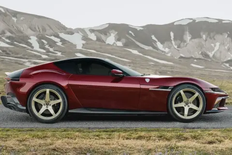 Czerwone Ferrari LaFerrari z złotymi felgami na tle górskich krajobrazów.