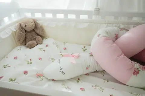 En söt sovorm med blomstermönster och en nalle i en spjälsäng.