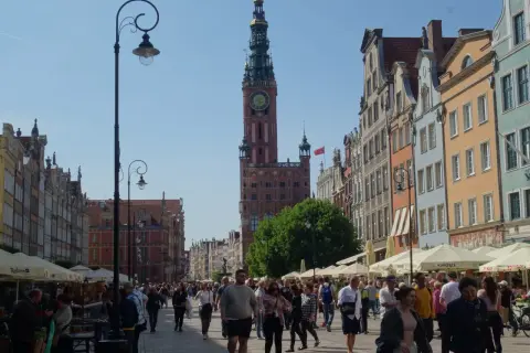 Piękna pogoda w Gdańsku w lipcu. Tłumy spacerują ulicą Długą podziwiając kamienice i Ratusz.
