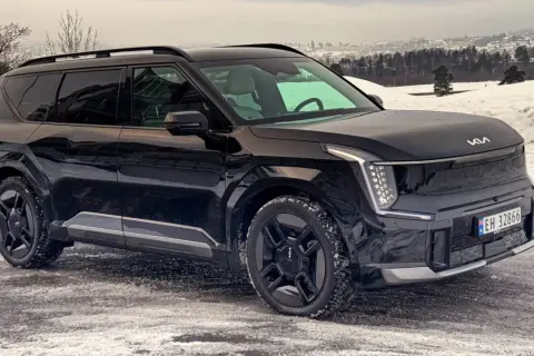 Svart Kia EV9 på en snöig väg, redo för ett vintertest. Bilen har en modern design med distinkta LED-lampor.