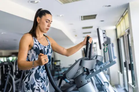 Frau trainiert auf einem Crosstrainer, um ihren Kalorienverbrauch zu steigern.