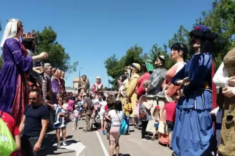 Gigantes y cabezudos desfilan en las fiestas del Parque Goya. Niños y adultos disfrutan de la colorida procesión bajo el sol.