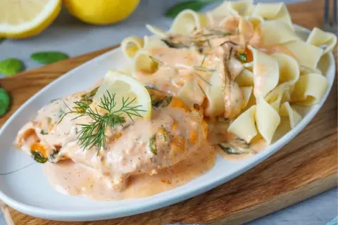 Zartes Lachsfilet in cremiger Sahnesauce mit Dill und Zitrone, serviert mit breiten Bandnudeln. Ein köstliches Lachs Sahne Gratin.