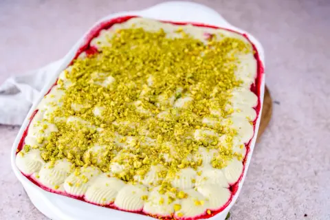 Ein cremiges Pistazien Tiramisu in einer weißen Auflaufform, bestreut mit gehackten Pistazien.