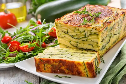 Un flan de courgettes à préparer la veille, aux couches fines et dorées, servi avec une salade fraîche. Parfait pour un repas léger.