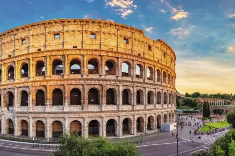 Colosseum i Rom, en ikonisk gammal stad i Italien, badar i gyllene solljus. Turister promenerar på torget framför den imponerande amfiteatern.