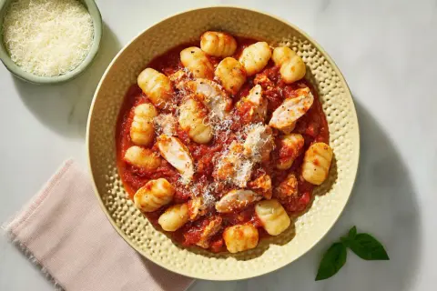 Pyszne gnocchi z kurczakiem w sosie pomidorowym, posypane parmezanem.