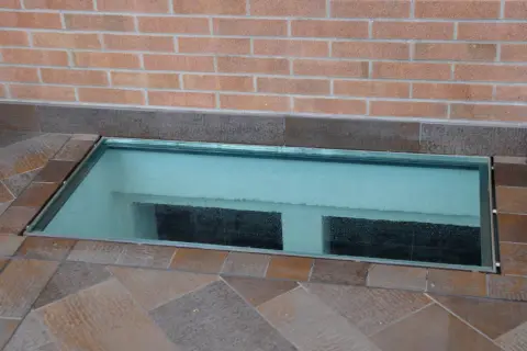 Bocche di lupo come coprirle: una soluzione moderna con una lastra di vetro trasparente che illumina l'interrato.