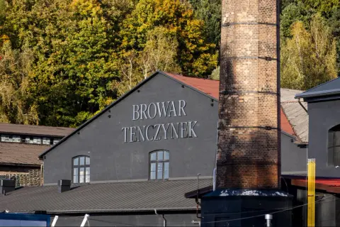 Browar Tenczynek, z charakterystycznym kominem i jesiennymi drzewami w tle. Właściciel dba o tradycję.