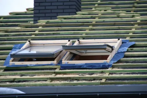 Dach prefabrykowany w budowie, z widocznymi oknami dachowymi i drewnianą konstrukcją.